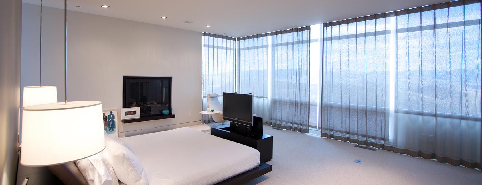 Modern Park City bedroom featuring automated motorized window shades, recessed LED lighting, and smart lighting controls for energy-efficient ambiance and comfort